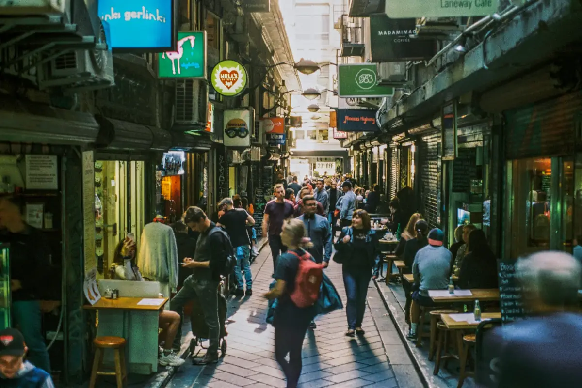 A busy Melbourne laneway lined with cafes, people walking between the tables.