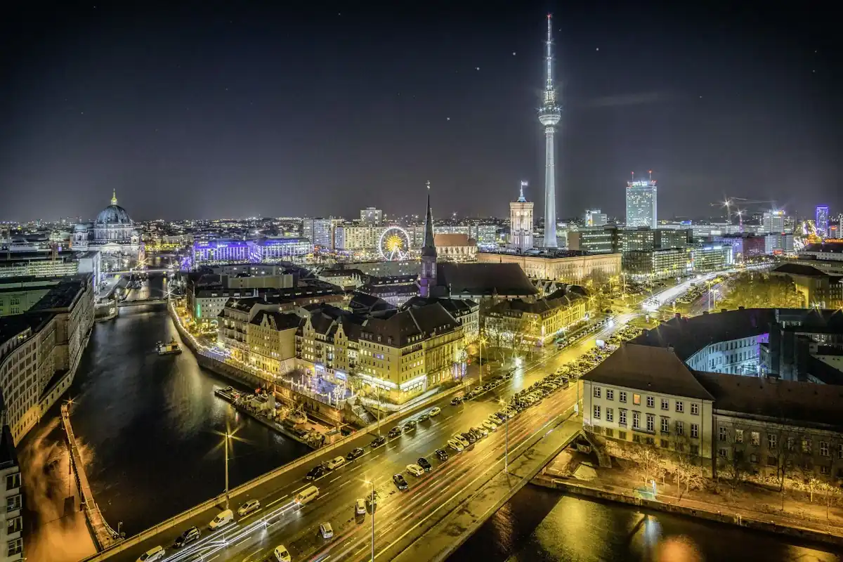 Berlin at night, with the TV tower rising above the Spree and the lit-up city center.