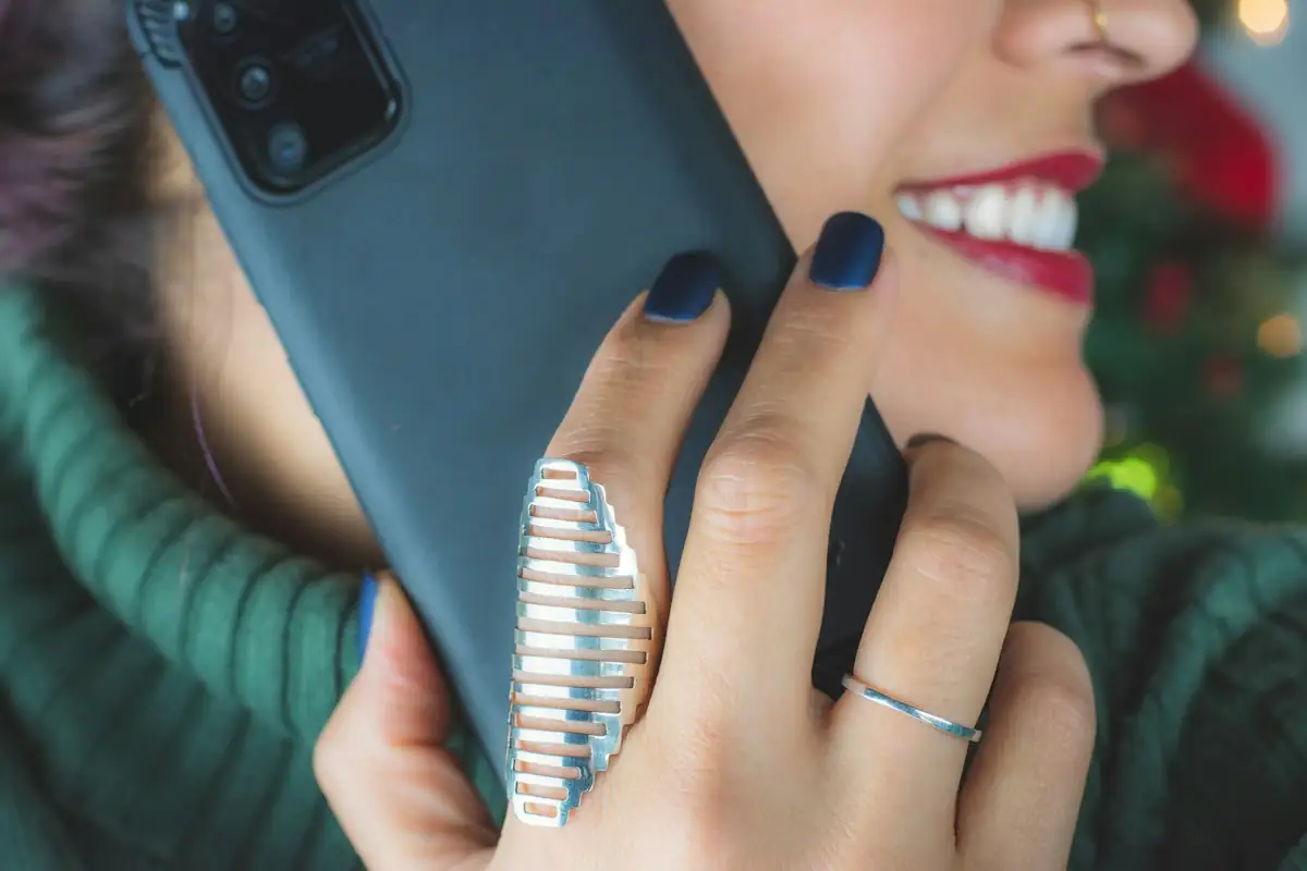 A smiling woman holding a smartphone to her ear during a call.