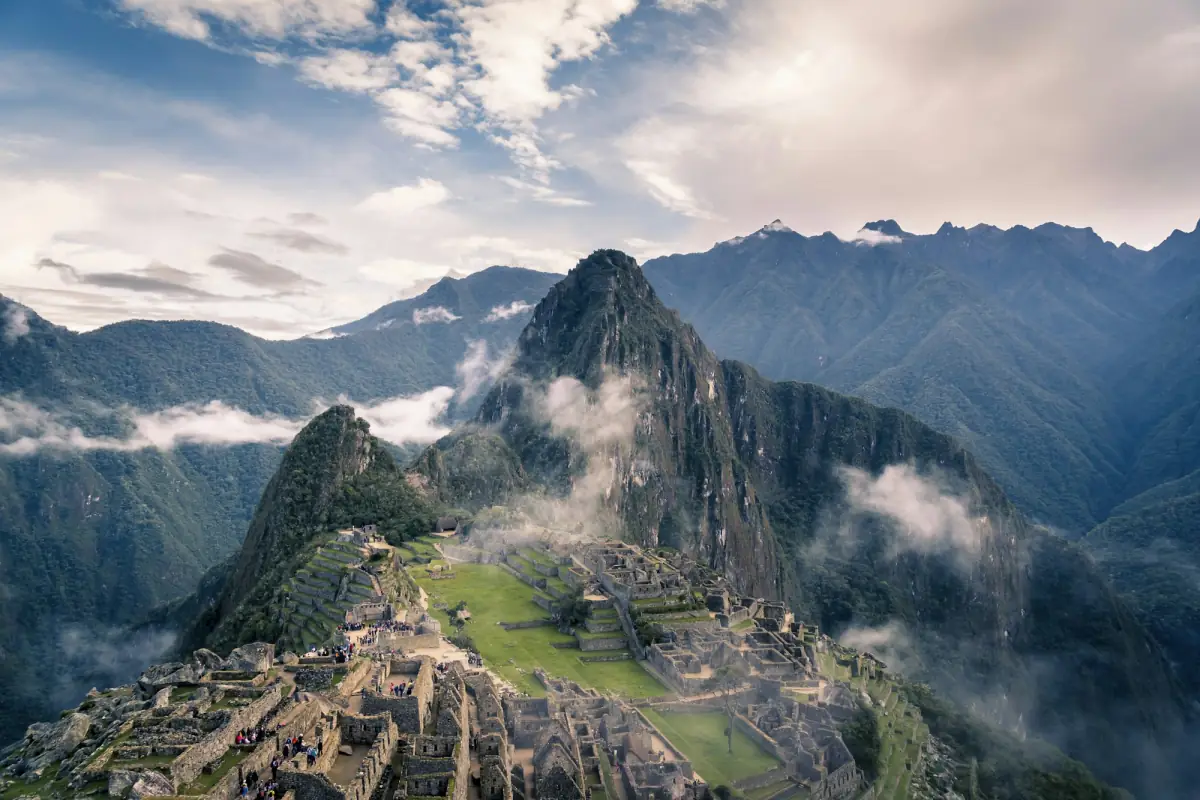 The ruins of Machu Picchu below Huayna Picchu, with clouds drifting over the peaks.