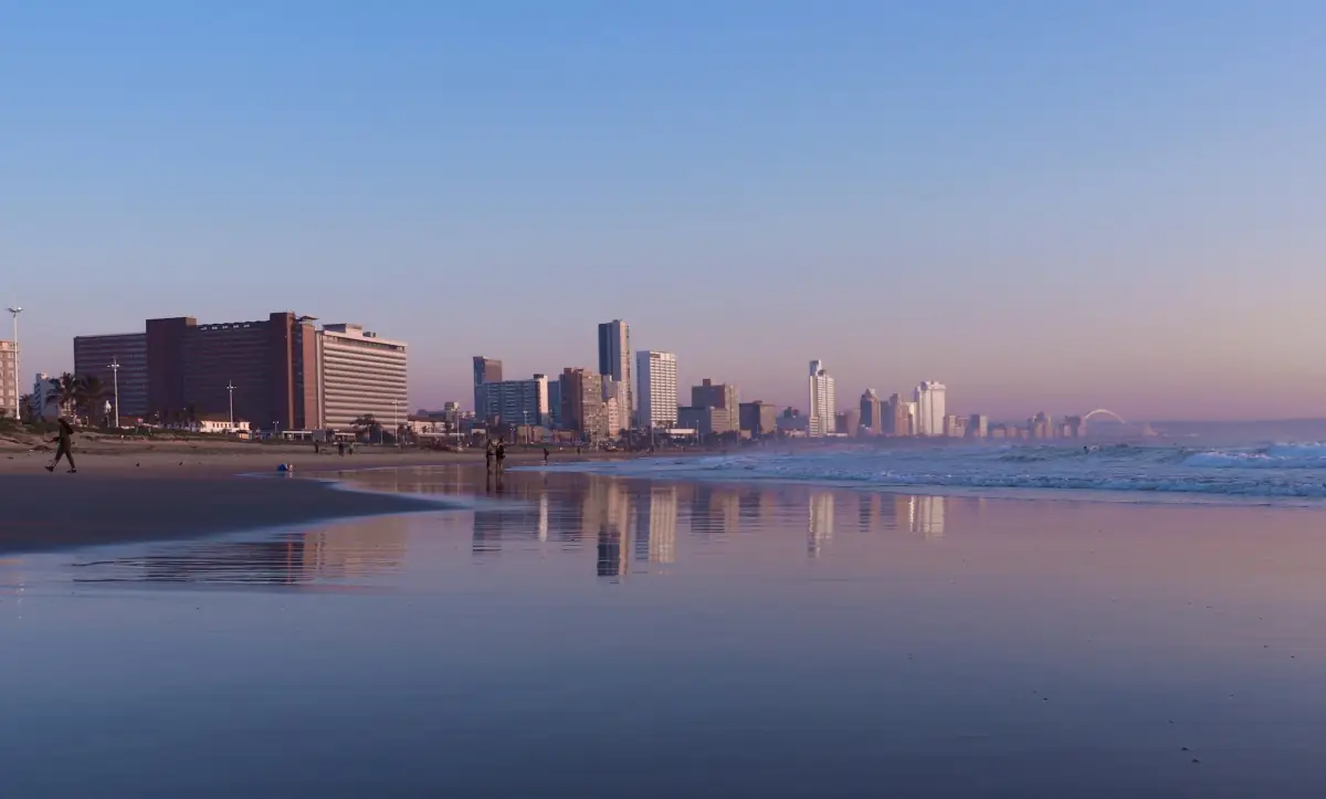 The Durban beachfront and its hotels reflected in wet sand at dusk.