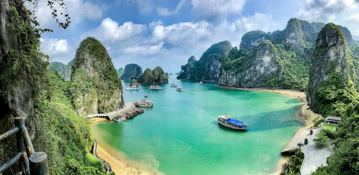 Limestone islands and a small boat on the turquoise water of Ha Long Bay.