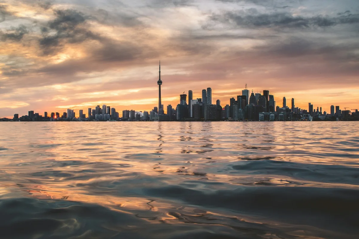The Toronto skyline and the CN Tower seen across Lake Ontario at sunset.