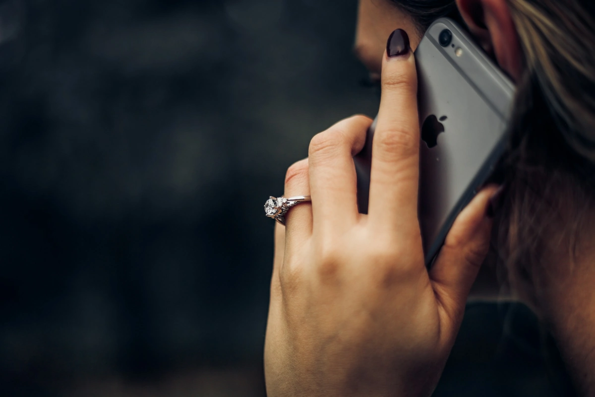 Close-up of a hand holding a smartphone to someone's ear during a call.